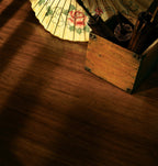 Wooden box with pencils on a wooden surface, illuminated by a lamp with floral design.