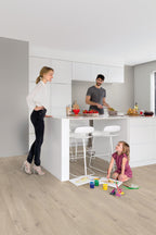 Family in a modern kitchen with white cabinets and wooden flooring.