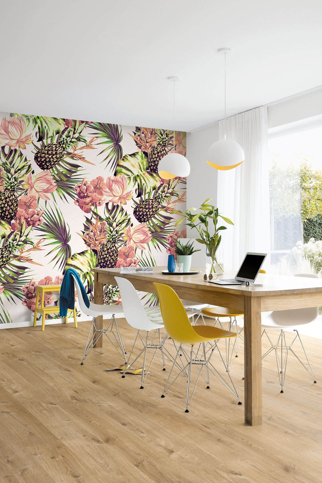 Modern office with colorful floral wall mural, wooden desk, and colorful chairs.