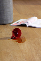 Red cup spilled on a wooden floor with an open magazine nearby