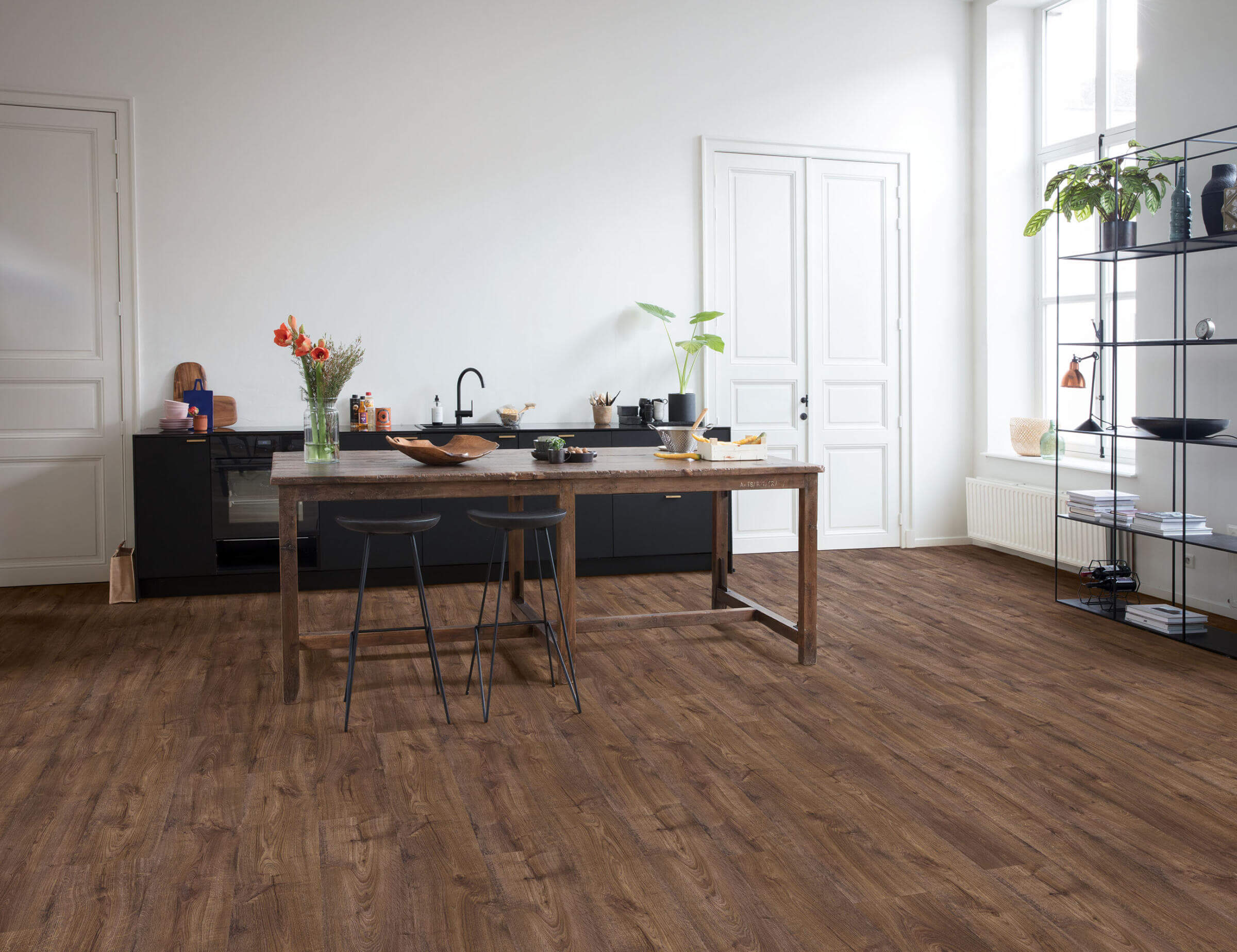 Modern kitchen with wooden flooring, table, and chairs.