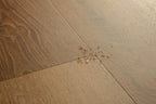 Wooden floor with a small cluster of gold beads on it