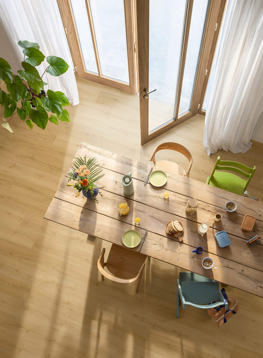 Dining area with a wooden table, chairs, and decorative items in a bright room.
