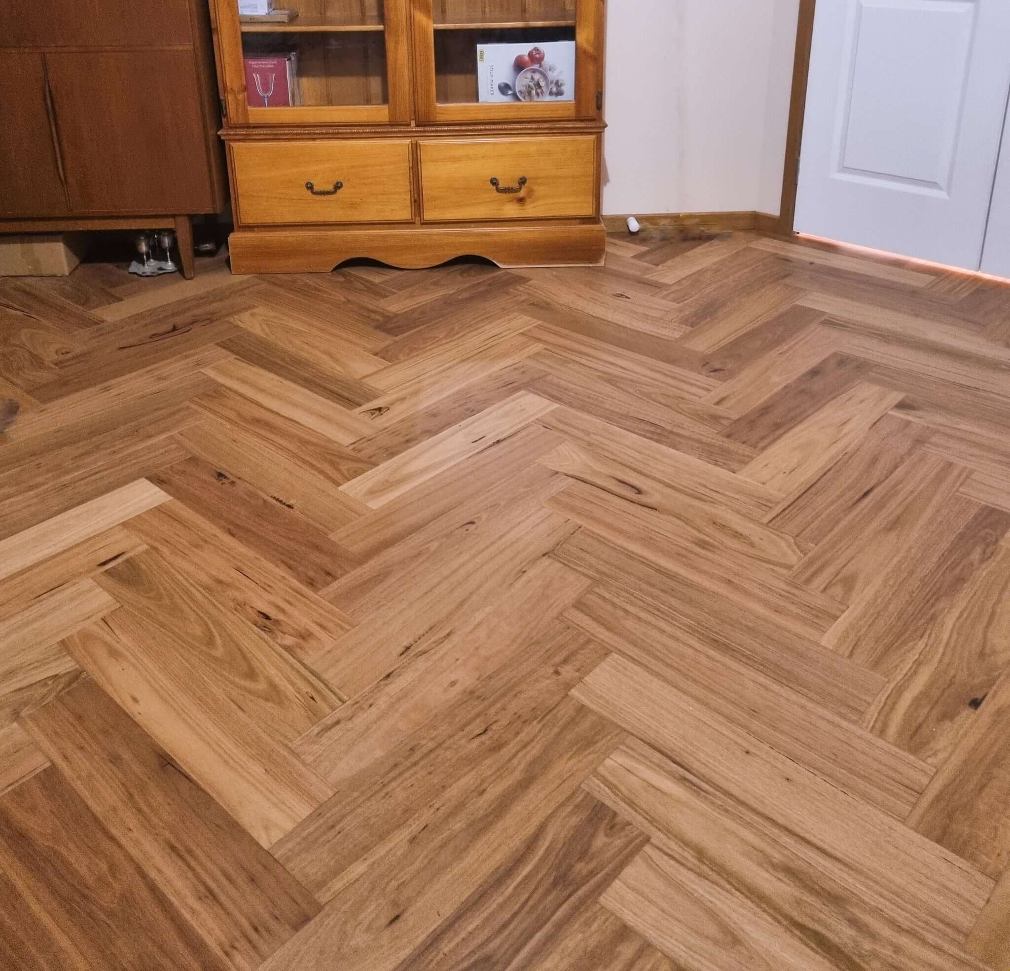 Wooden floor with herringbone pattern in a room with wooden furniture.