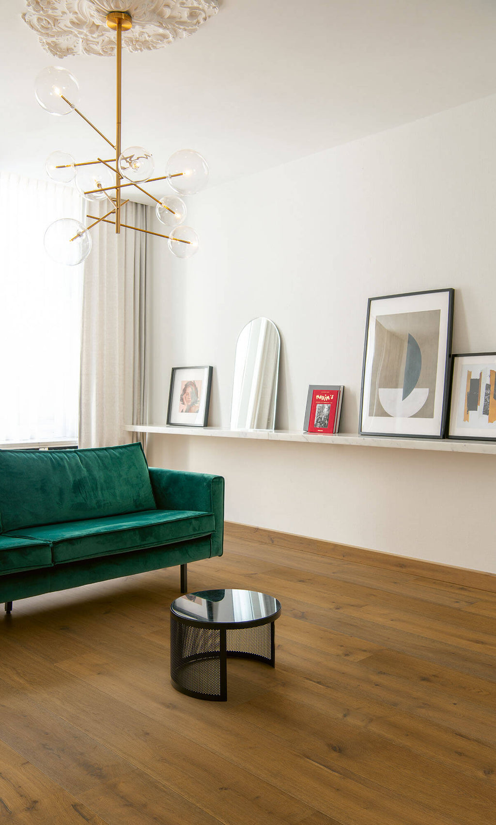 Modern living room with a green sofa, round coffee table, and wall art.