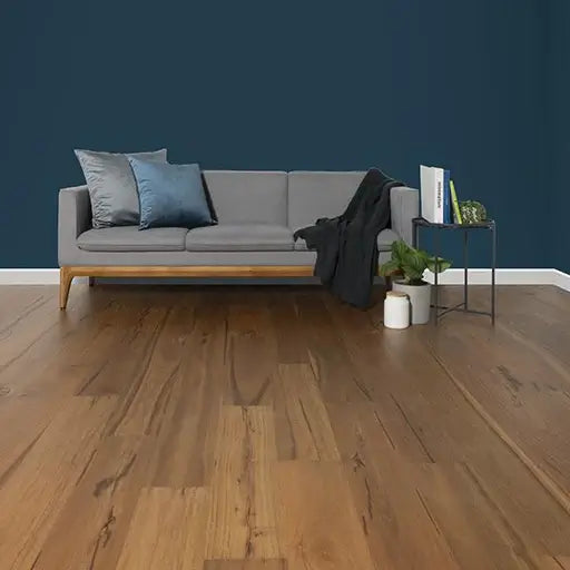 Gray sofa with decorative pillows against a blue wall in a room with wooden flooring.