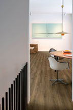 Modern interior with wooden flooring, white chair, and abstract painting on the wall.