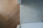 Wooden floor with a herringbone pattern next to a tiled wall and white radiator.