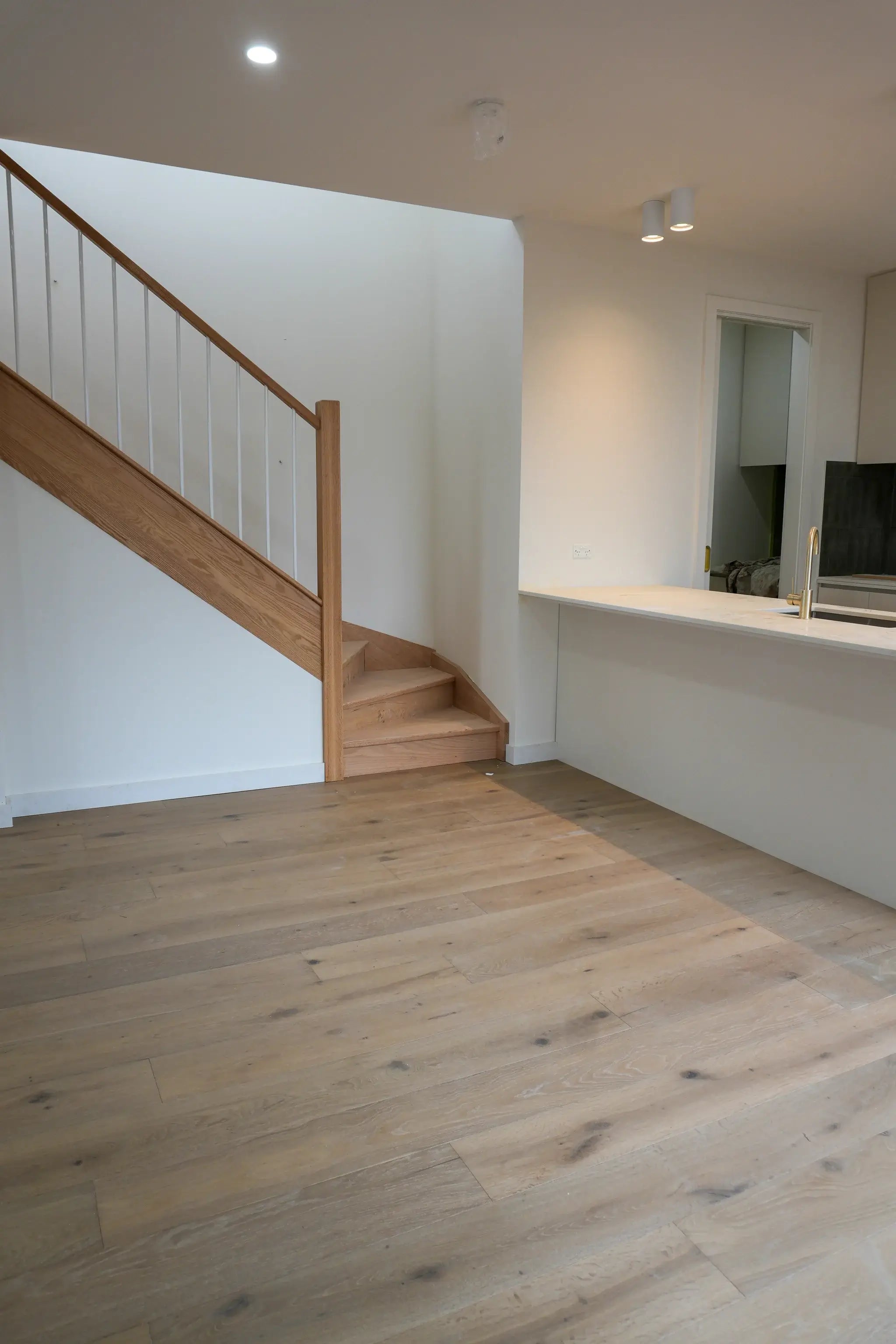 Wooden staircase in a modern interior setting with light wood flooring.