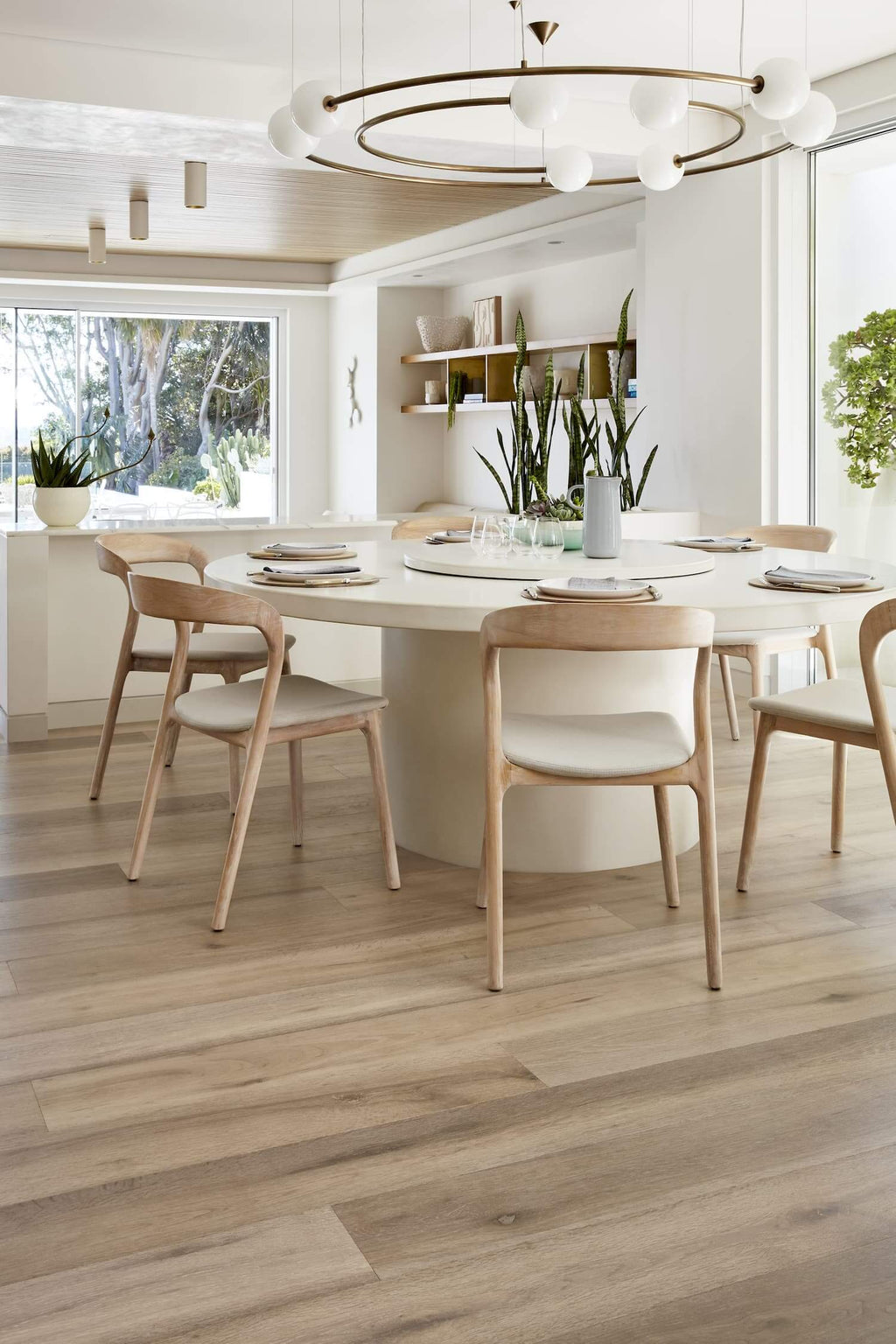 Modern dining room with a white table and wooden chairs in a bright, naturally lit space.