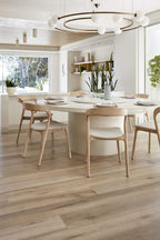 Modern dining room with a white table and wooden chairs in a bright, naturally lit space.