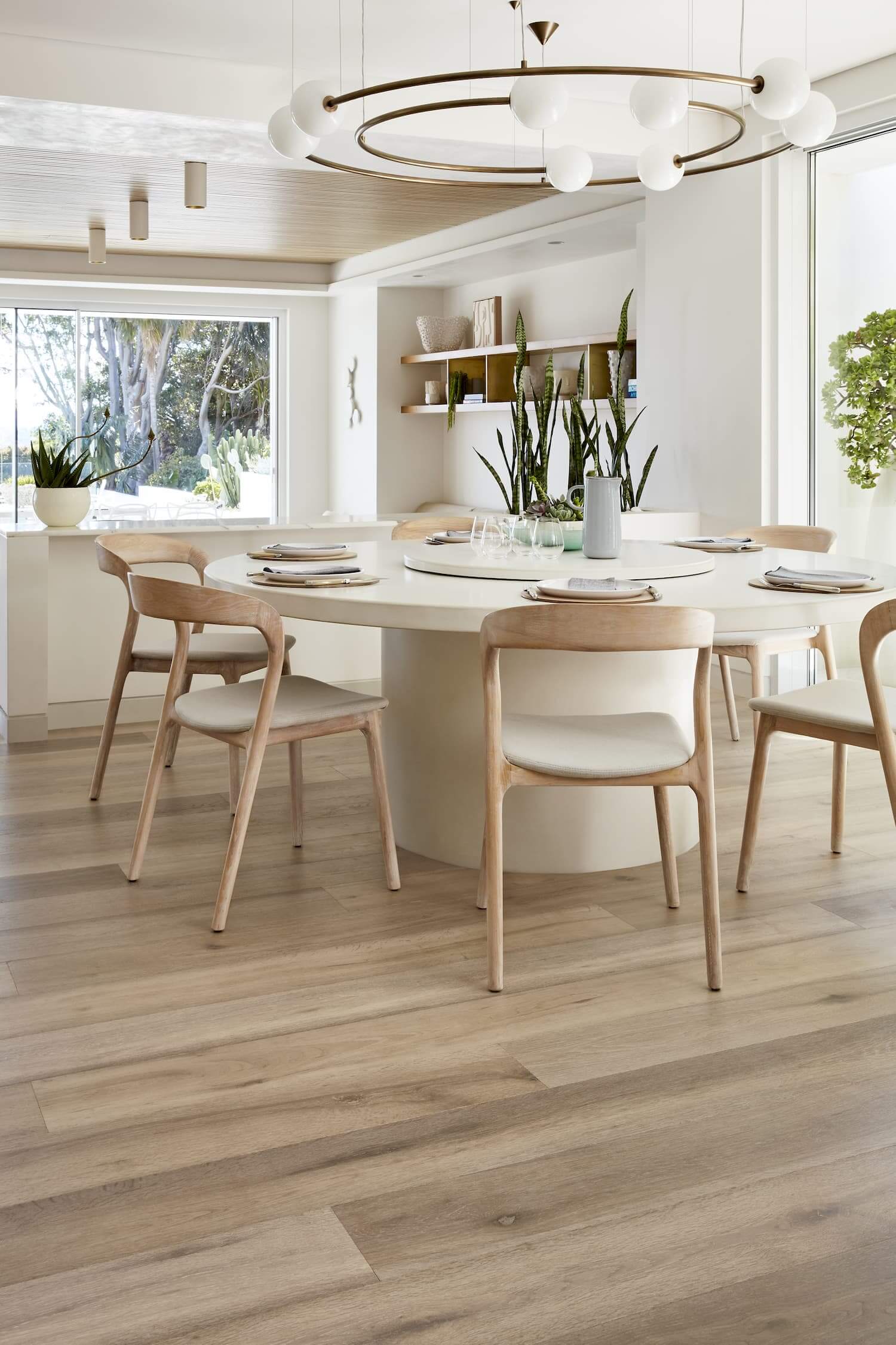 Modern dining room with a white table and wooden chairs in a bright, naturally lit space.