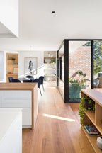 Modern kitchen with wooden floor, white walls, and large windows.