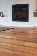 Wooden floor with a fireplace in a room with white walls and a rug.
