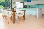 Modern kitchen with wooden dining table and chairs, light blue backsplash, and white cabinets.