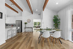 Modern kitchen and dining area with wooden floors and white walls.