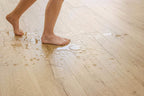 Person walking on a wet wooden floor with water damage.