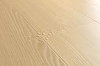 Light beige wood-look floor planks with visible grain texture and a small cluster of water droplets in the center.