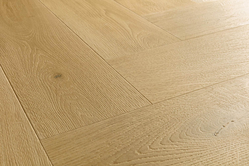 Light oak wood flooring planks arranged in a herringbone pattern, showing natural wood grain and subtle knots.