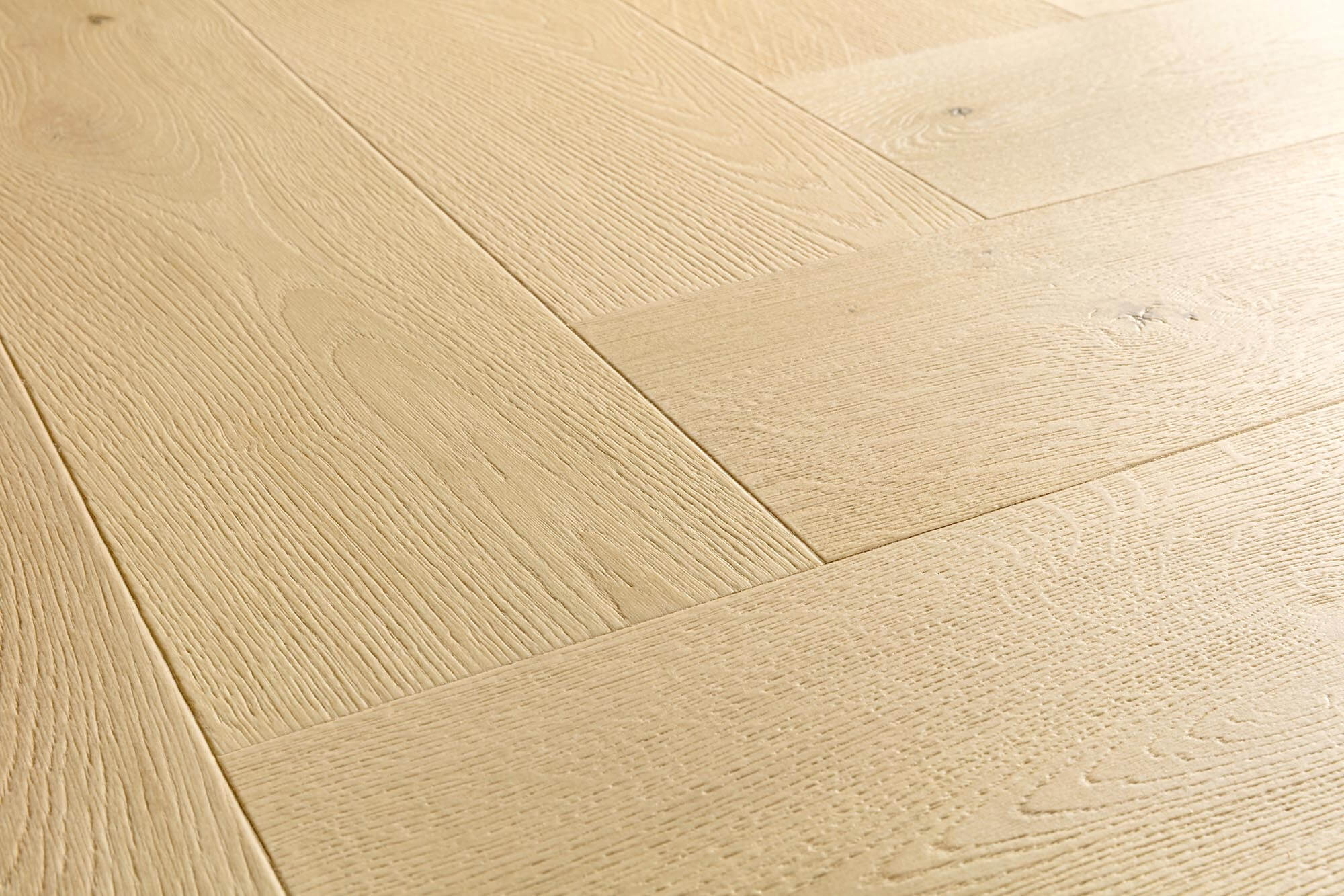 Light natural oak wood flooring planks arranged in a herringbone pattern, showing detailed wood grain and subtle knots.