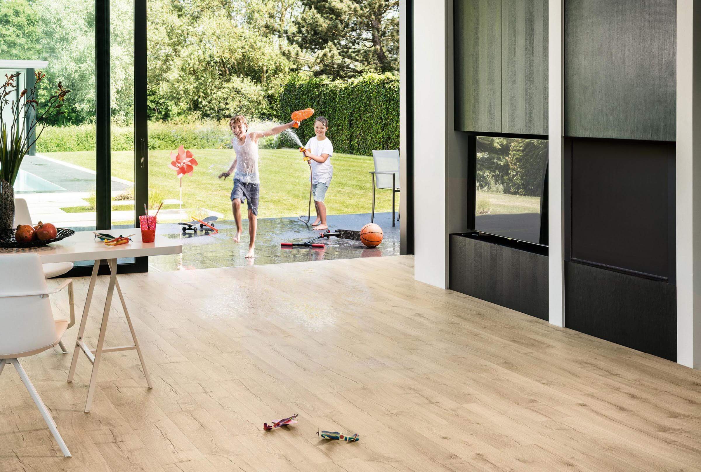 Modern living room with wooden flooring, large windows, and a view of a garden.