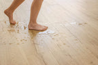 Person walking on a wooden floor with water stains