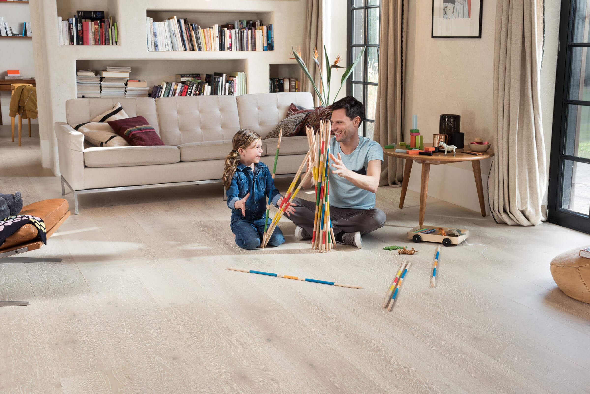 Man and child playing with colorful sticks in a living room.