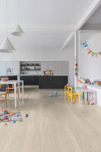 Modern kitchen with light wood flooring and children's toys scattered around.