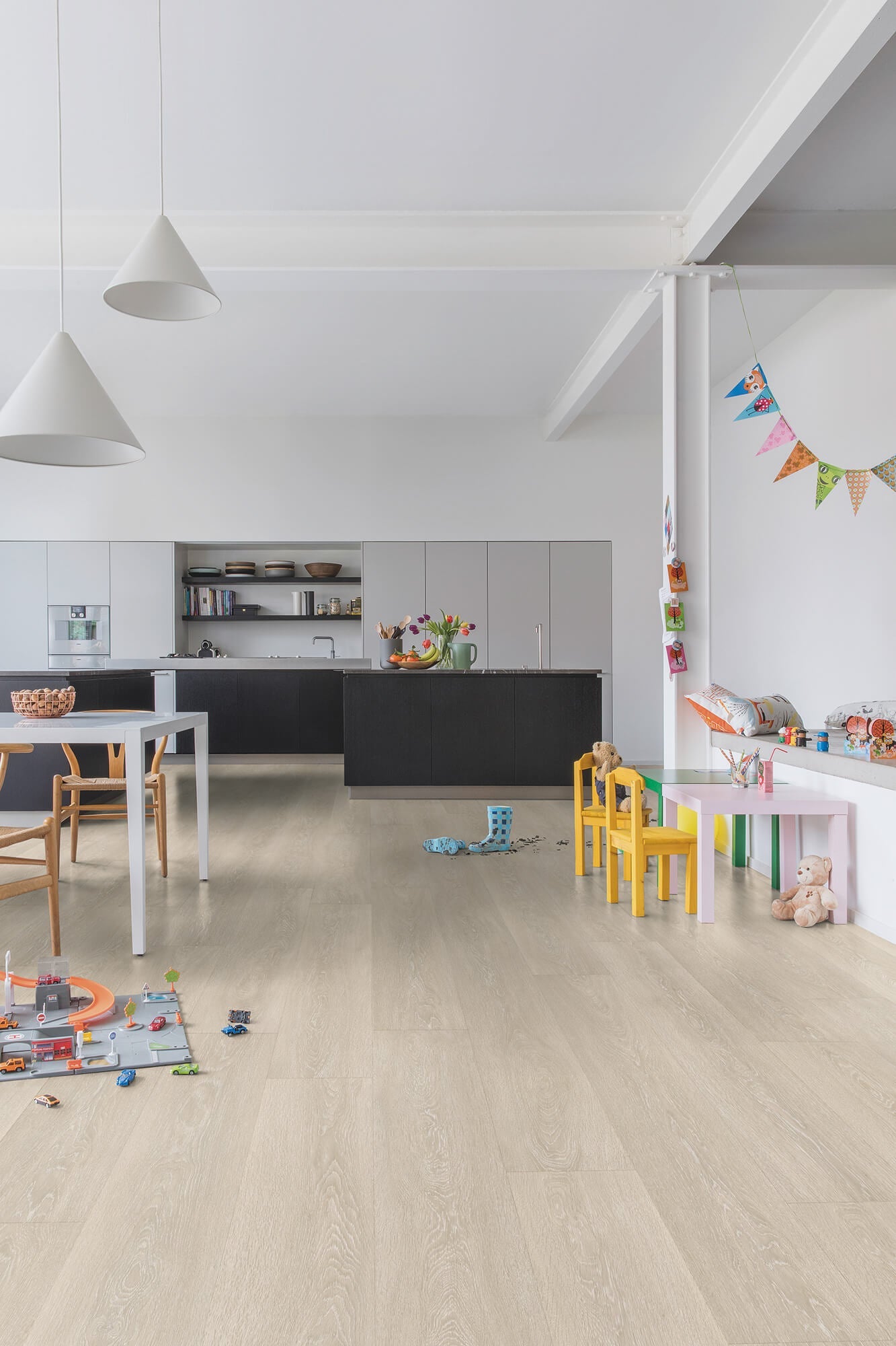 Modern kitchen with light wood flooring and children's toys scattered around.