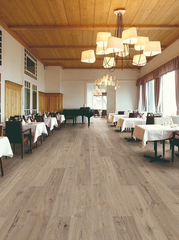 Large room with wooden flooring, tables, chairs, and chandeliers.
