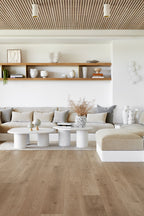 Modern living room with wooden floor, white walls, and neutral color furniture.