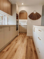 Modern kitchen with wooden flooring and light-colored cabinets.