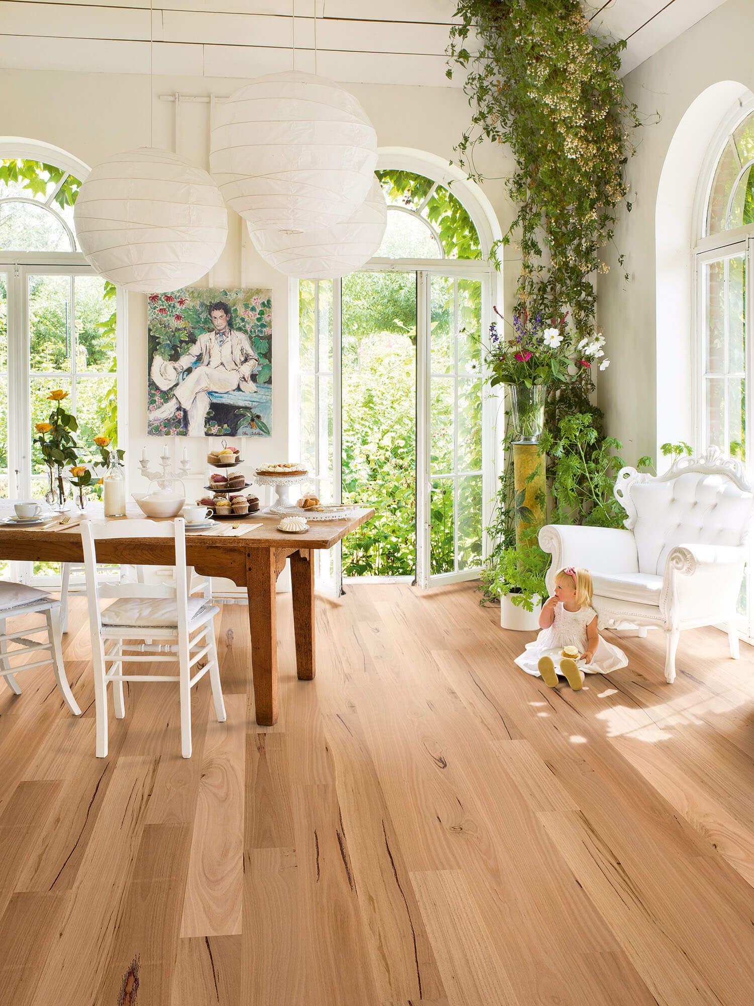 Brightly lit room with wooden floor, dining table, and large windows.