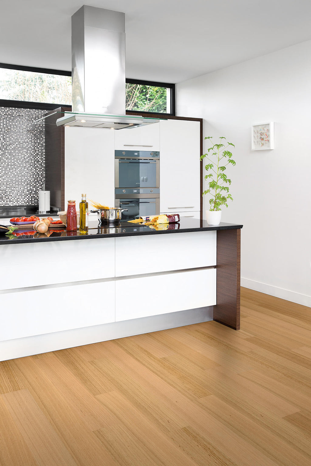 Modern kitchen with white cabinets, black countertop, and wooden floor.