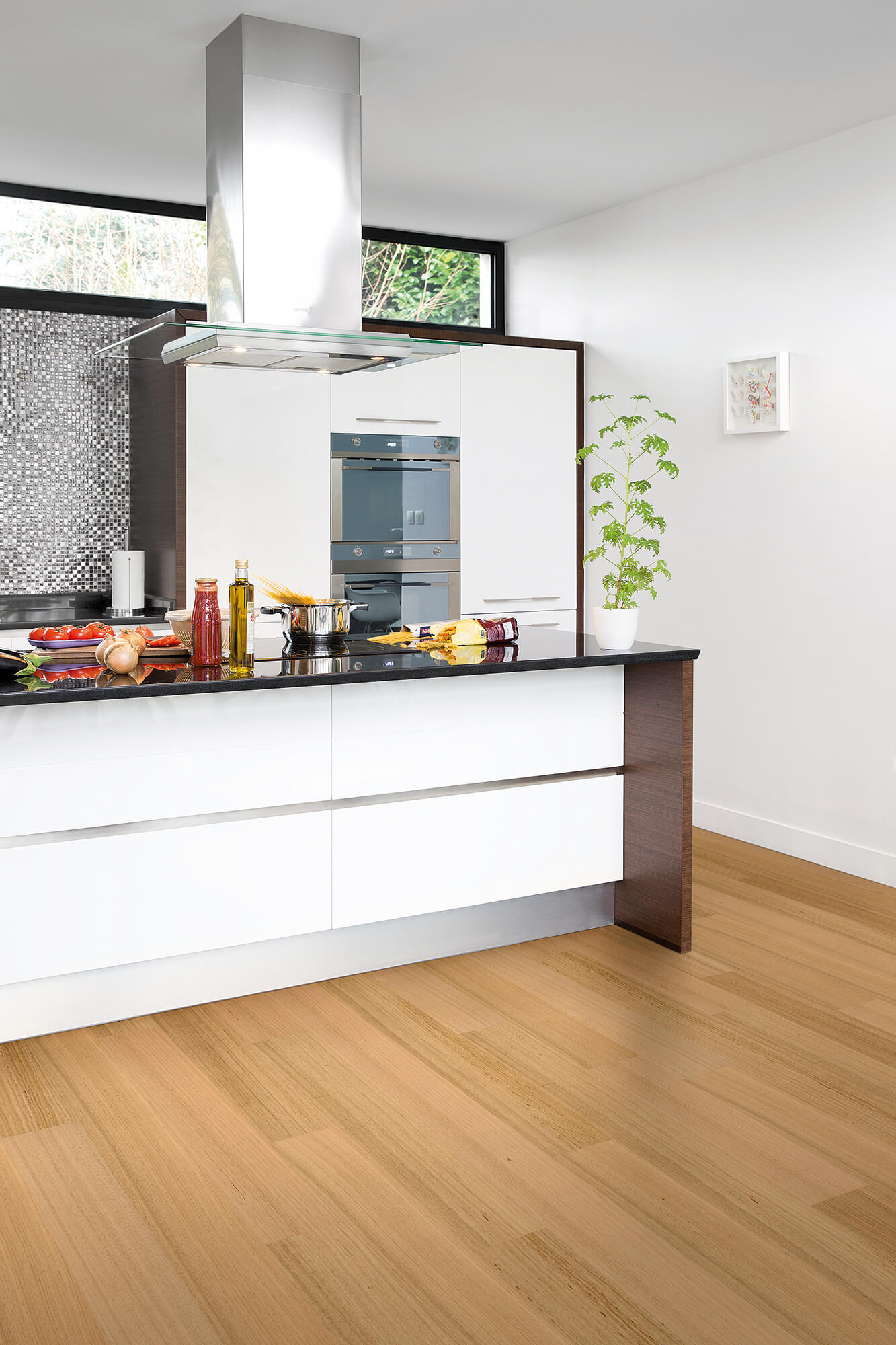 Modern kitchen with white cabinets, black countertop, and wooden floor.