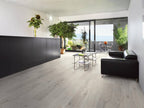 Modern living room with black sofa, glass coffee table, and large windows.