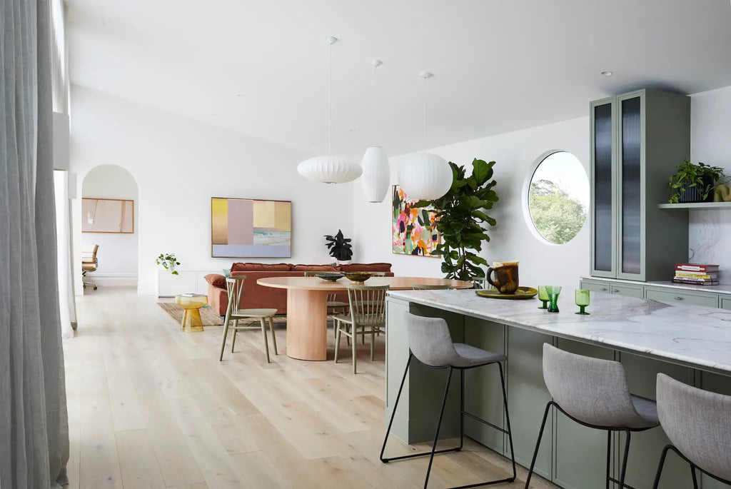 Modern kitchen and dining area with white walls and light wood flooring.