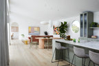 Modern kitchen and dining area with white walls and light wood flooring.