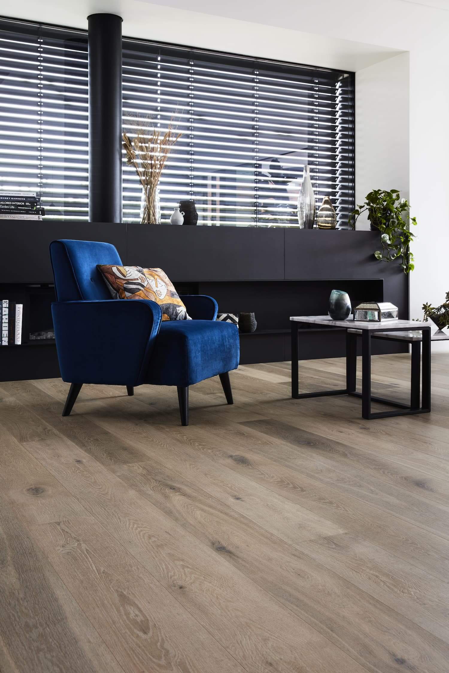 Modern living room with a blue armchair, wooden floor, and decorative items.