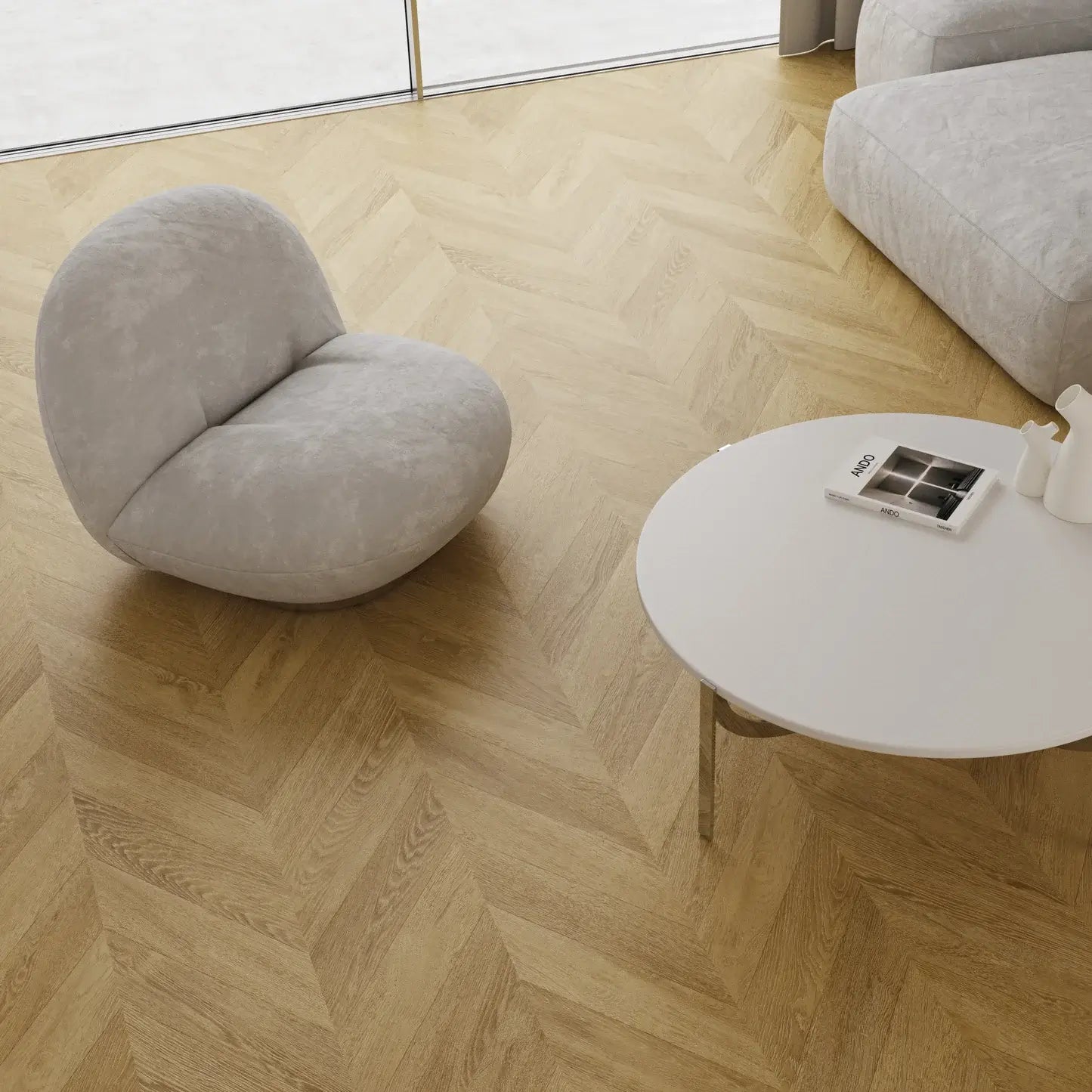 Modern living room with a gray sofa, armchair, and round coffee table on a wooden floor.