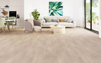 Modern living room with light wood flooring, furniture, and a painting on the wall.
