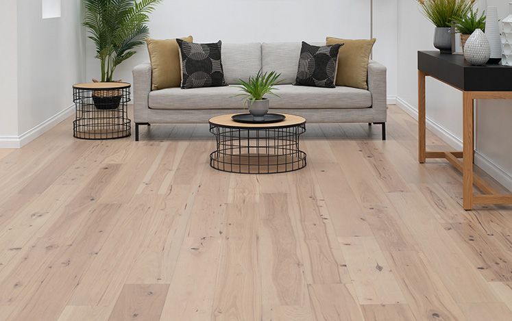 Living room with a gray sofa, coffee table, and decorative items on a wooden floor.