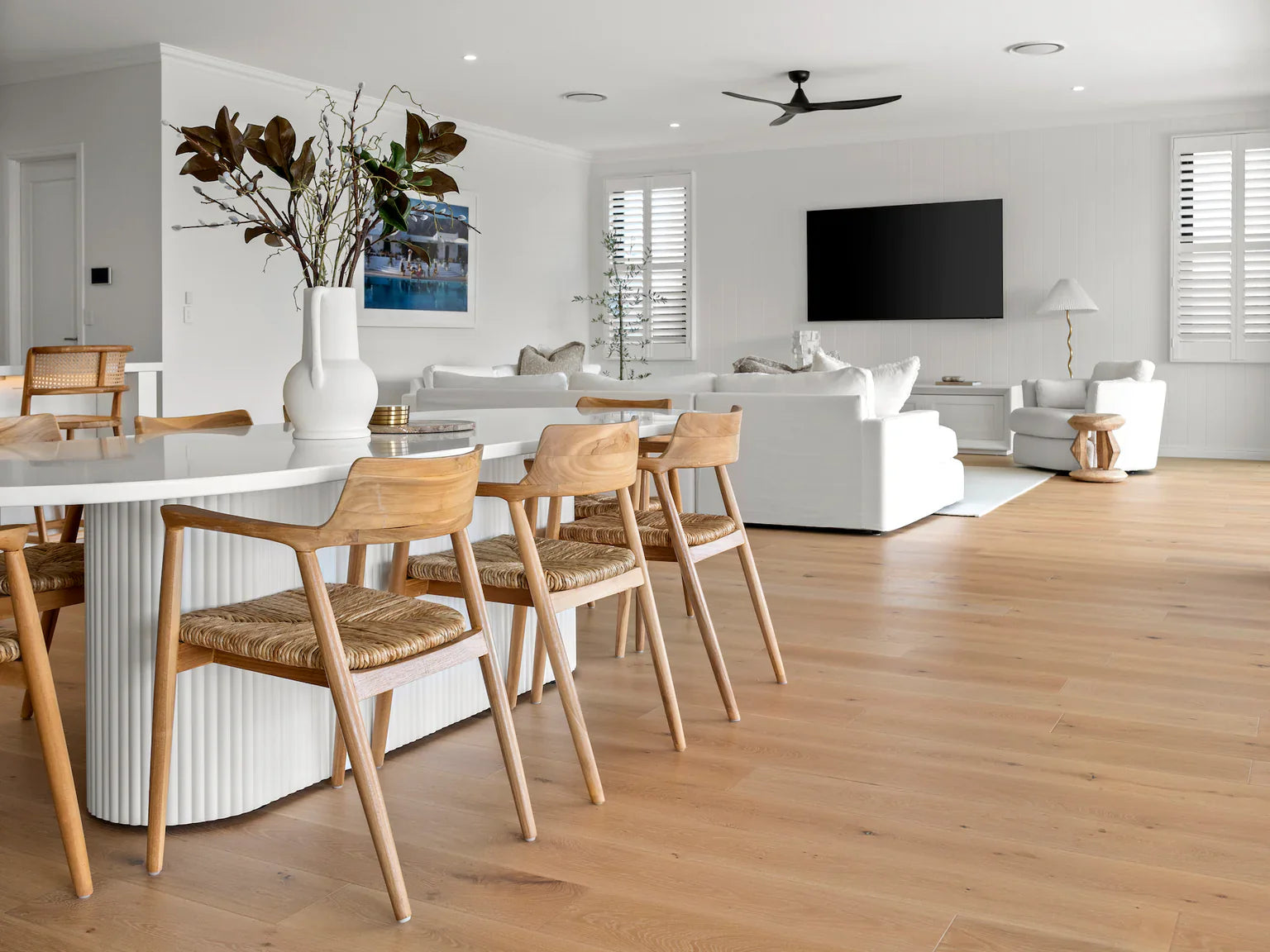 Modern living room with white furniture, wooden floor, and decorative elements.