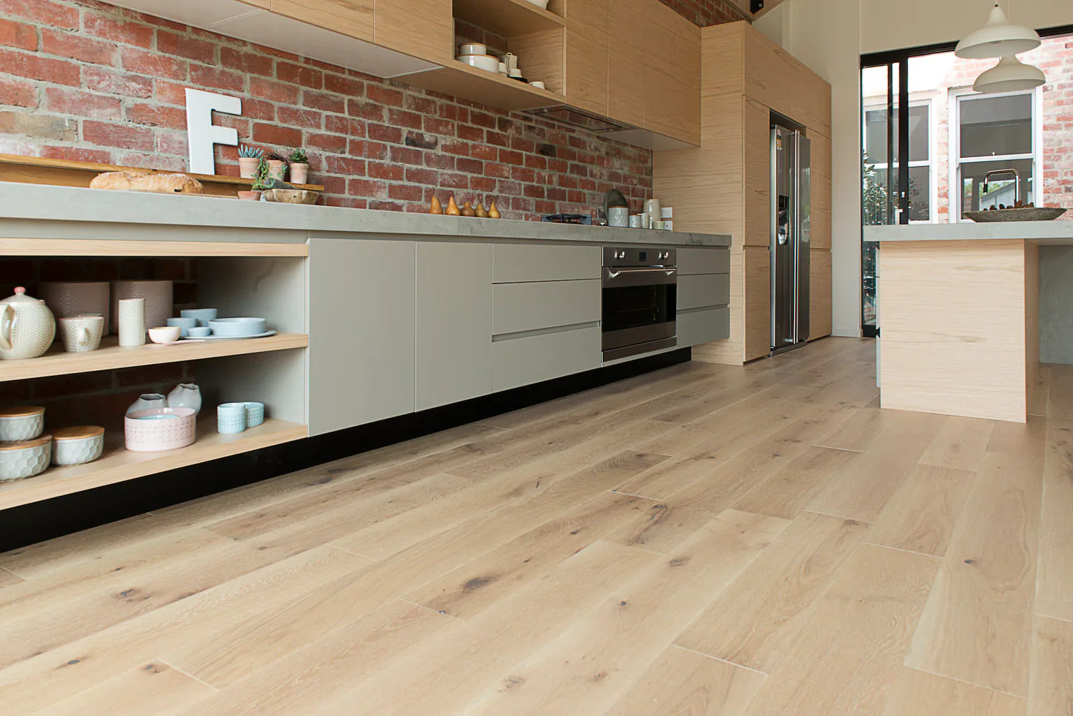 Modern kitchen with wooden flooring and brick wall