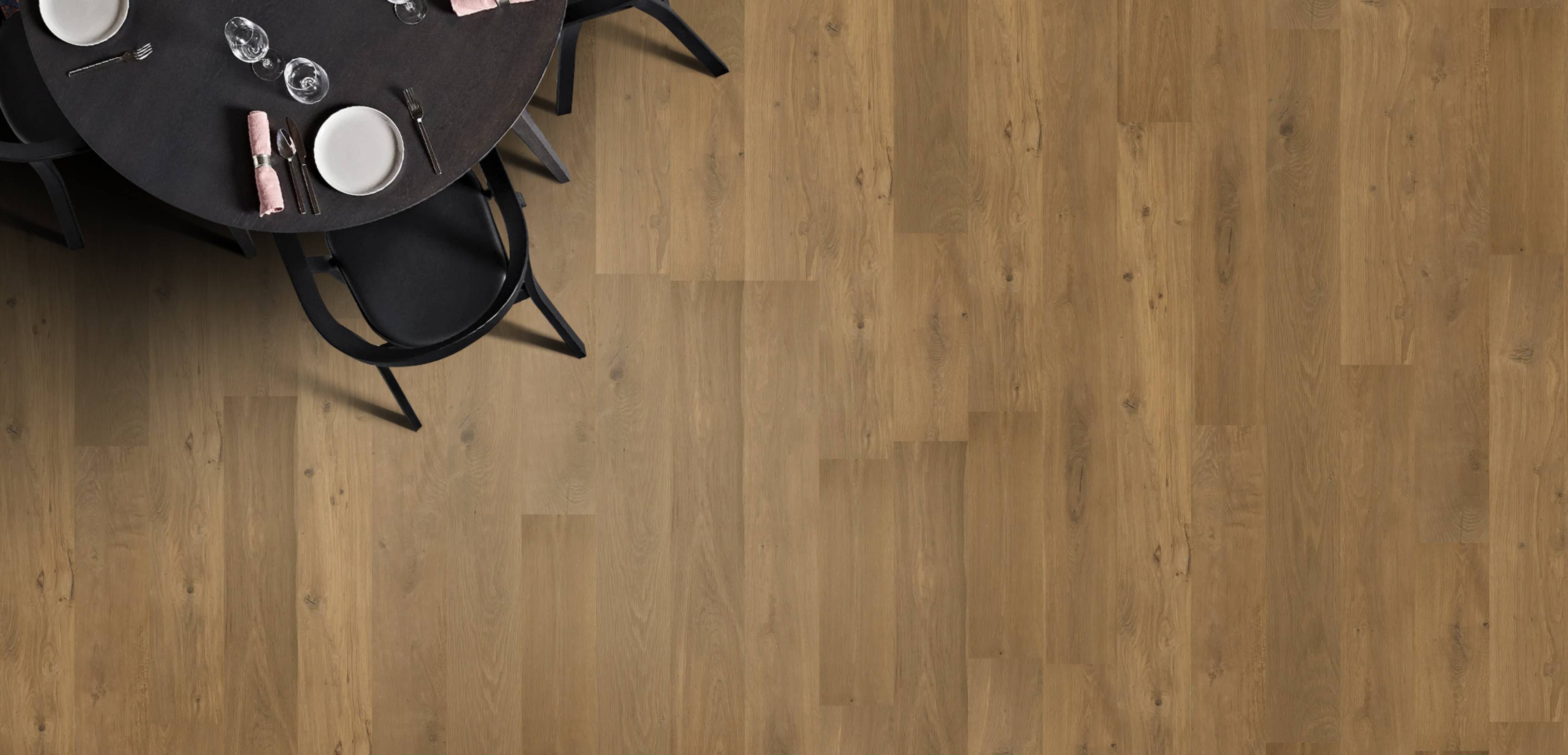 Wooden flooring with a black round table and chairs in the corner.