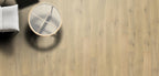 Wooden floor with a round mirror and a white cushion on a chair.