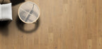 Wooden floor with a small round table and white cushioned chair.