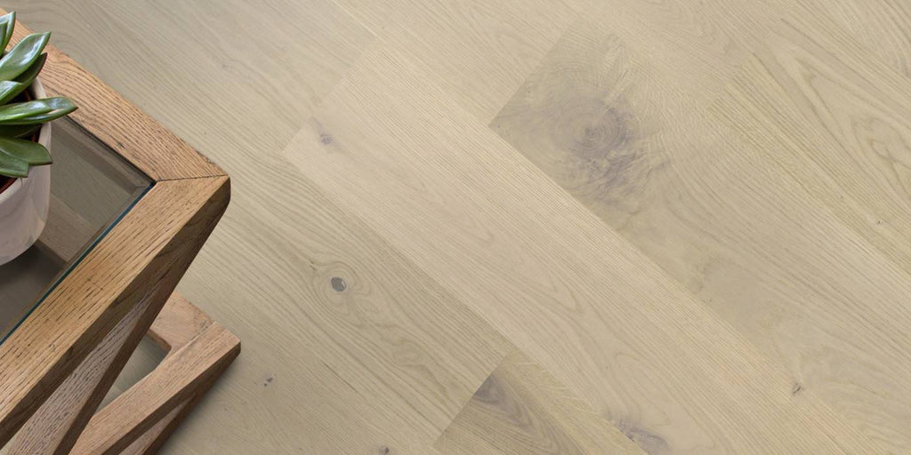 Wooden floor with a herringbone pattern and a wooden table with a plant on it.