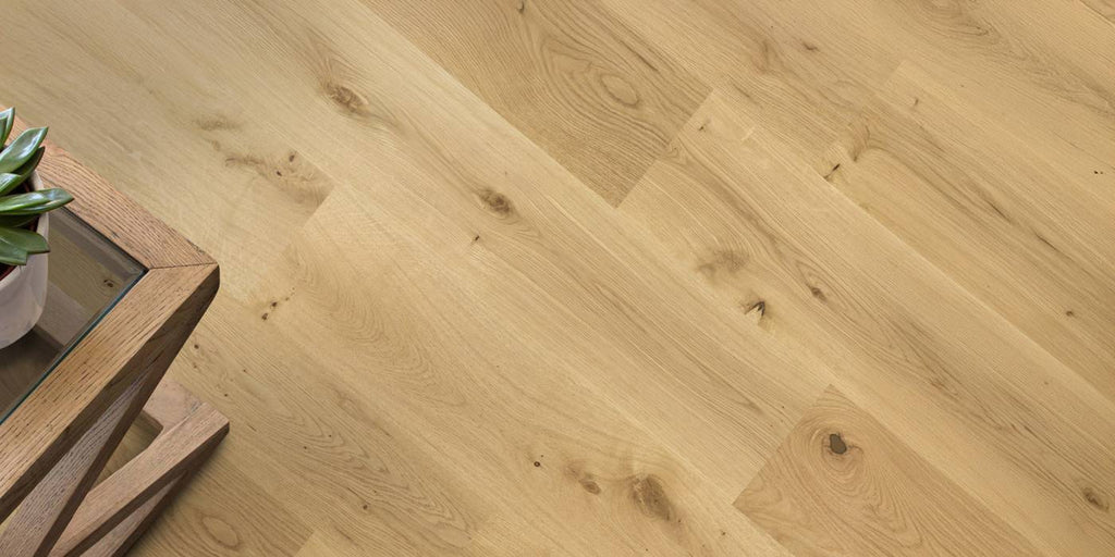 Wooden floor with a herringbone pattern and a small table with a plant on it.