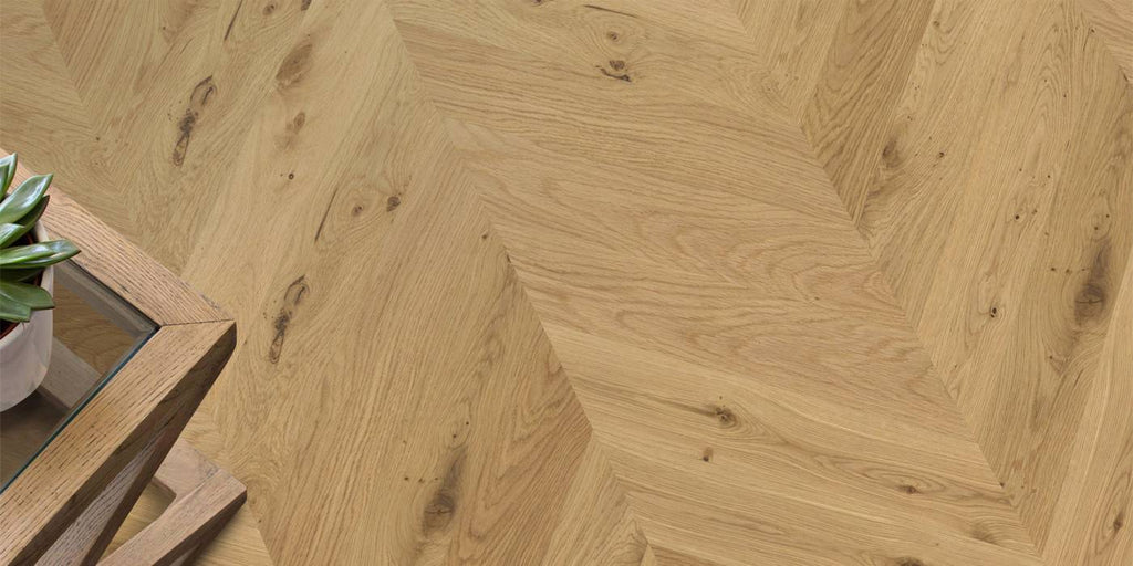 Wooden floor with herringbone pattern and a small table corner.